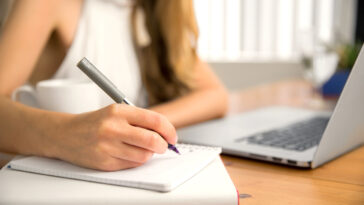 Close up student business hand laptop computer notes studying home